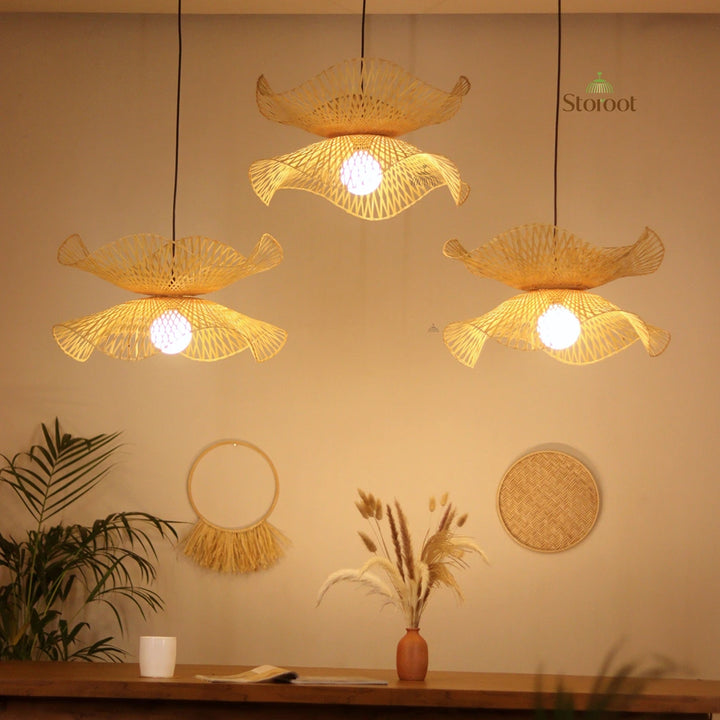 Woven bamboo pendant lights hanging above a 6 feet dining table with boho decorative items on a beige wall.